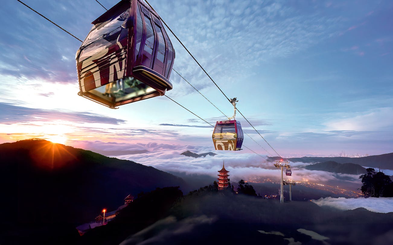 Genting Awana SkyWay cable car over misty mountains at sunrise.