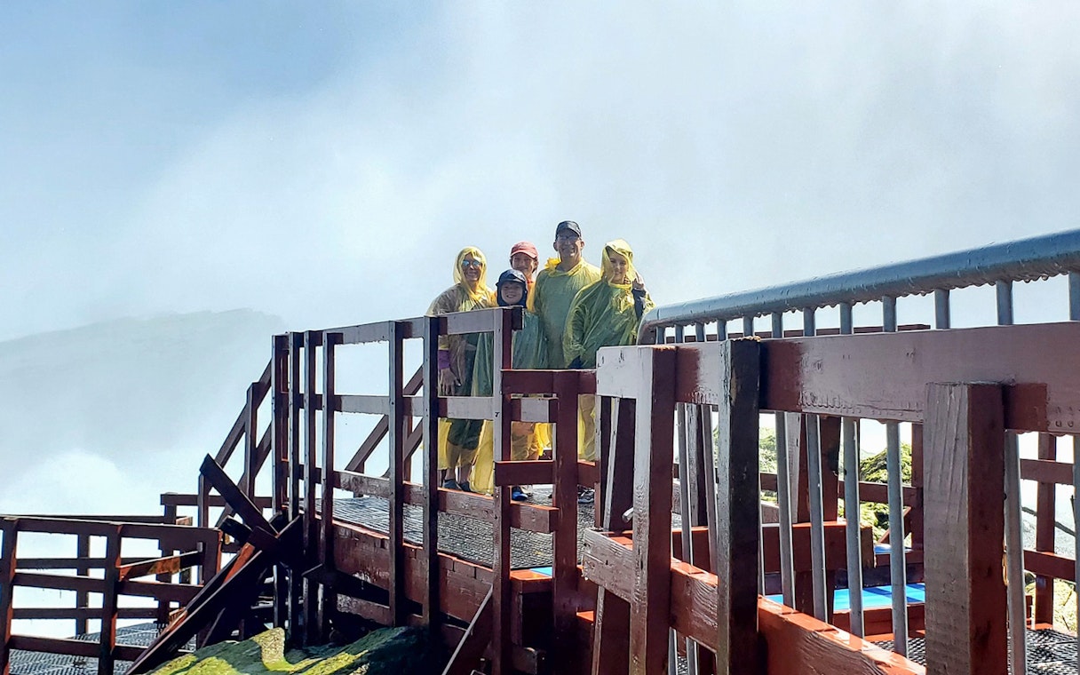 Visitors in rain ponchos on Cave of the Winds tour platform, Niagara Falls, New York.