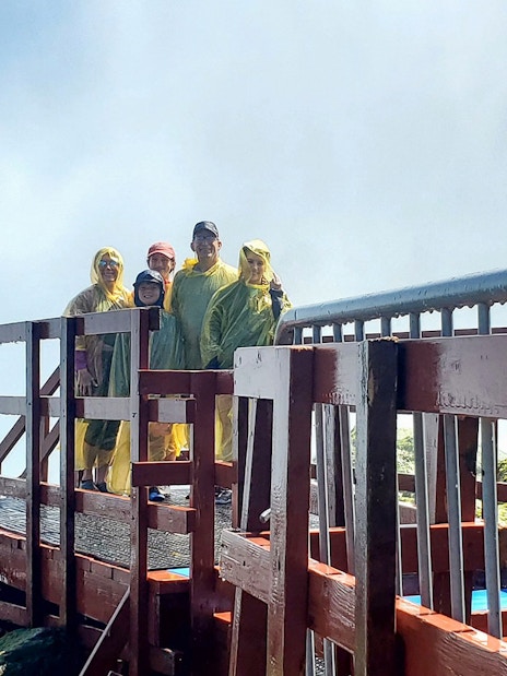 Visitors in rain ponchos on Cave of the Winds tour platform, Niagara Falls, New York.