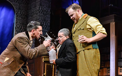 Actors in a comedic scene from "The Play That Goes Wrong" on stage.