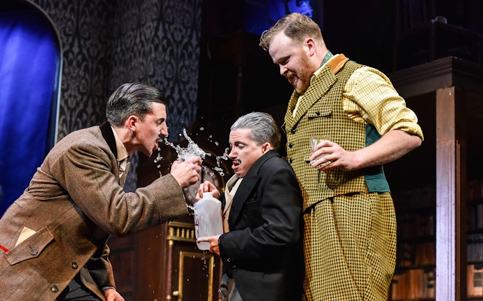 Actors in a comedic scene from "The Play That Goes Wrong" on stage.