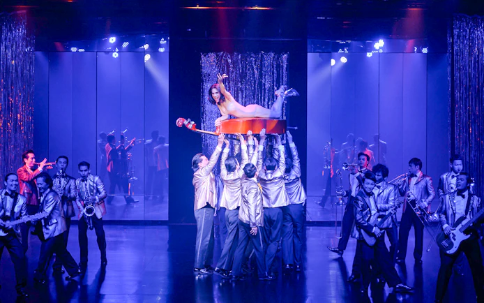 Performer on cello held by dancers at Calypso Cabaret, Bangkok.