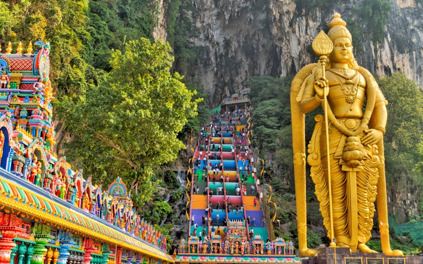 Golden statue and colorful temple steps at Batu Caves, Malaysia.