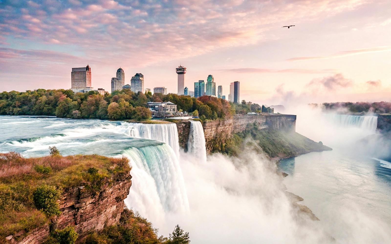 Niagara Falls with city skyline in the background at sunrise, USA.