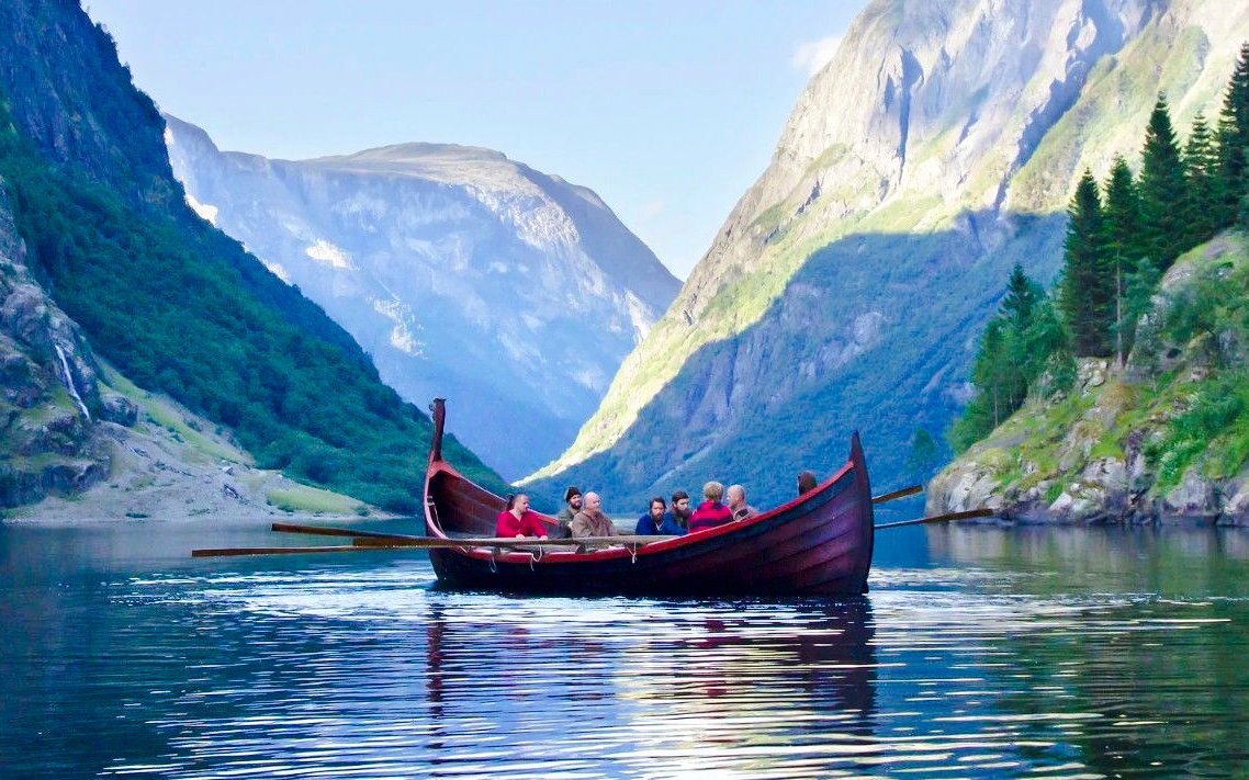 Boat cruise on Nærøyfjord with passengers surrounded by steep mountains.