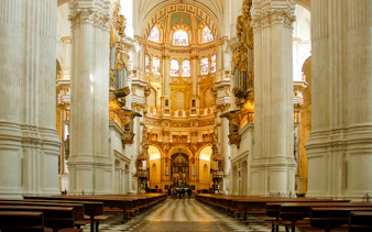 Interior view of the Royal Chapel of Granada with ornate columns and stained glass windows.