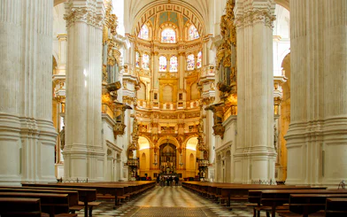 Interior view of the Royal Chapel of Granada with ornate columns and stained glass windows.