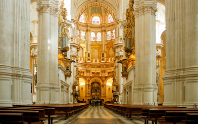 Interior view of the Royal Chapel of Granada with ornate columns and stained glass windows.