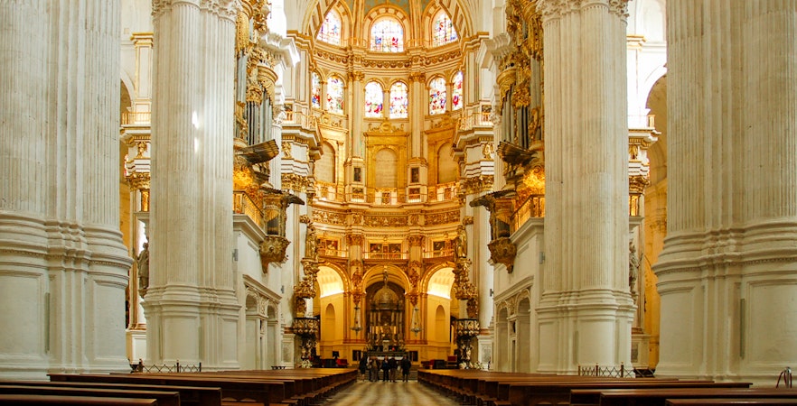 Interior view of the Royal Chapel of Granada with ornate columns and stained glass windows.
