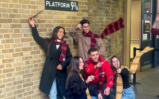 Visitors posing with wands at Kings Cross Platform 9 3/4 in London.