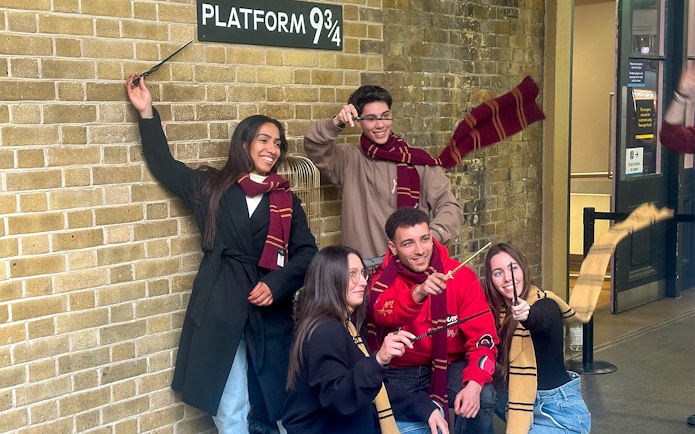 Visitors posing with wands at Kings Cross Platform 9 3/4 in London.