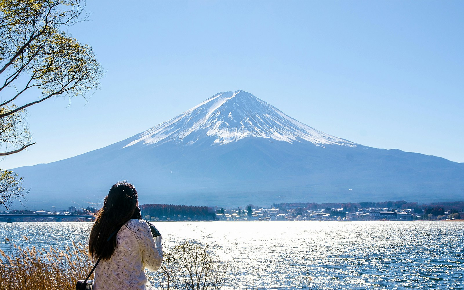 Woman sitting by Kawaguchiko Lake with Mount Fuji in the background, Japan.