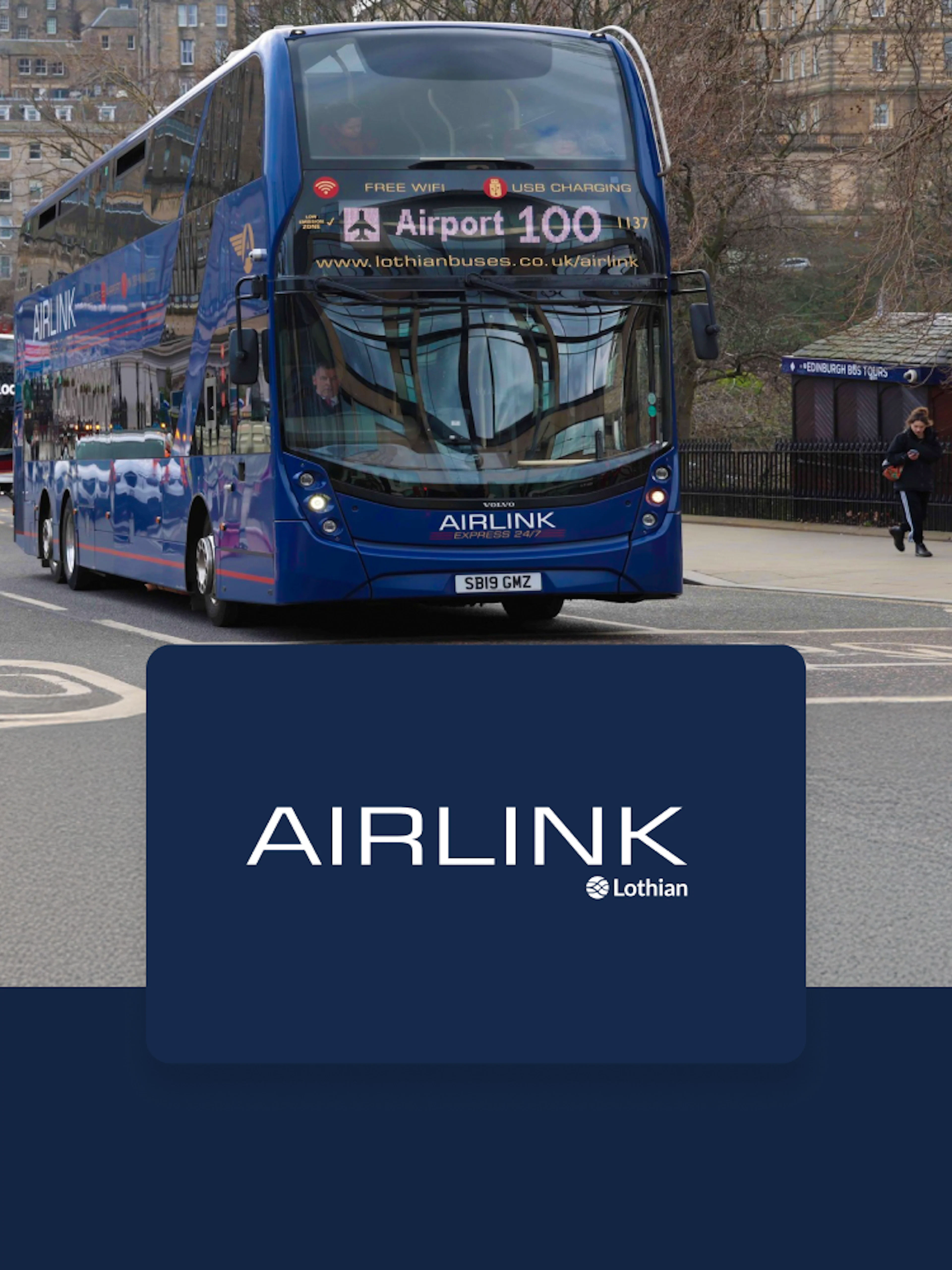 Edinburgh Airlink bus on city street near historic buildings.