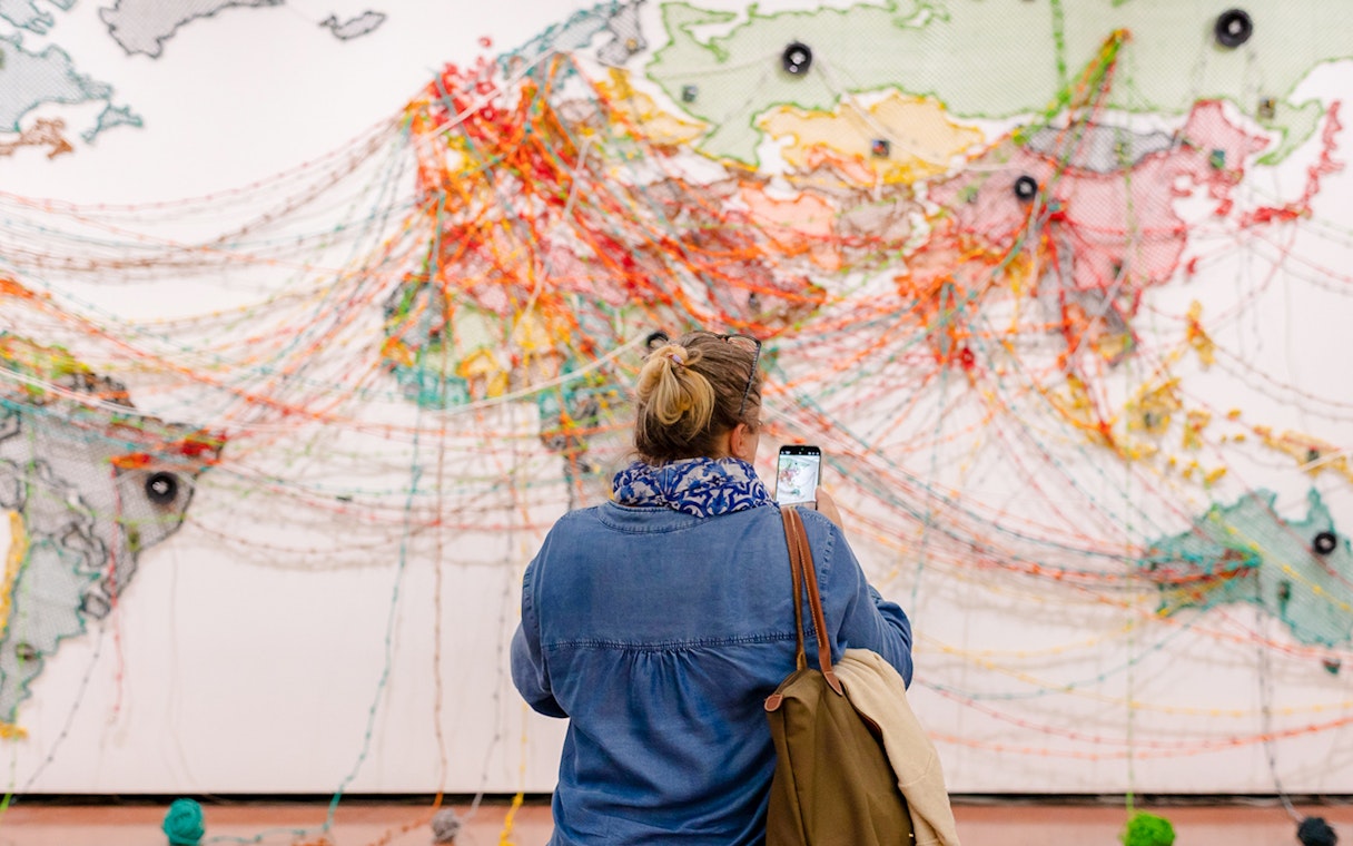 Visitor photographing colorful string art map at 'Die Linie' exhibition, Heidi Horten Collection Vienna.