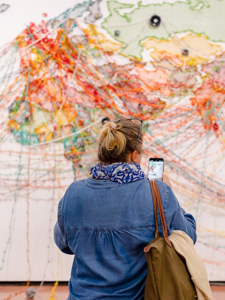 Visitor photographing colorful string art map at 'Die Linie' exhibition, Heidi Horten Collection Vienna.