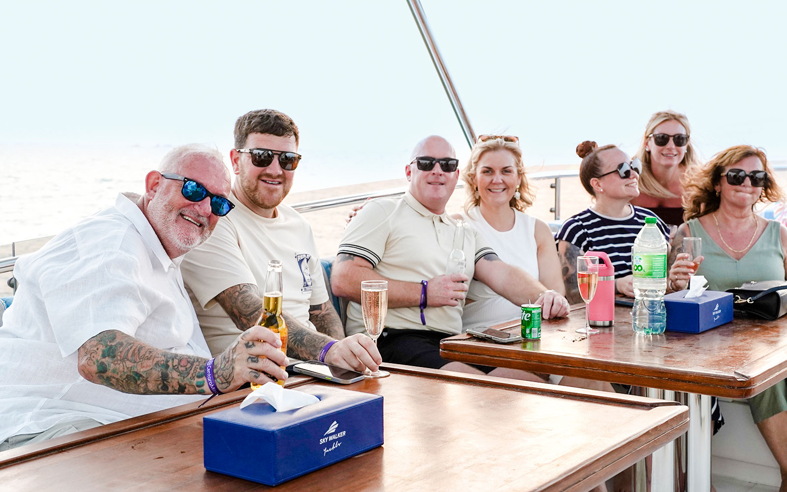 Family enjoying a yacht cruise in Dubai, seated at a table with drinks.