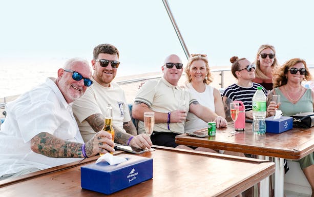 Family enjoying a yacht cruise in Dubai, seated at a table with drinks.