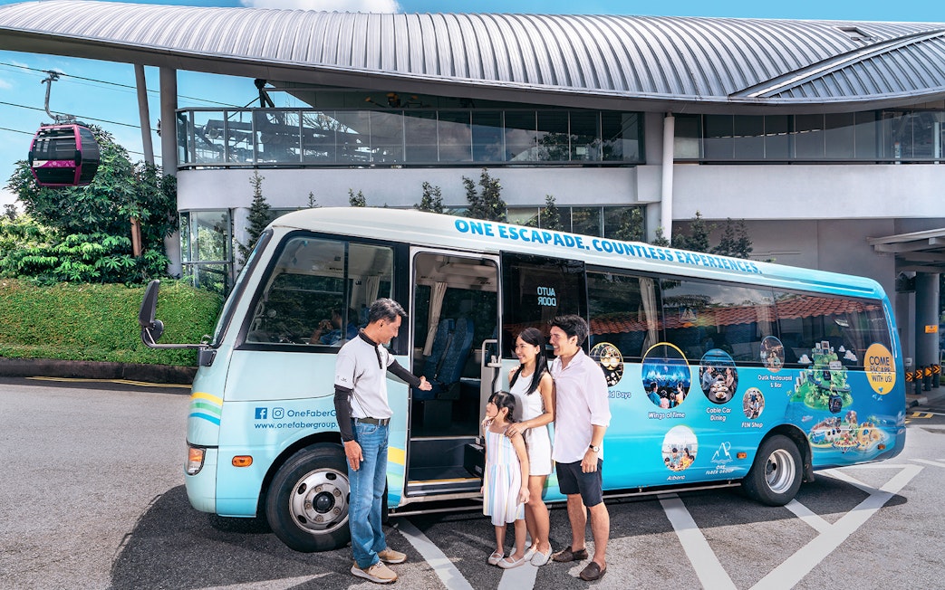 Family boarding a tour bus for Sentosa Island guided bus tour, with cable car station in background.