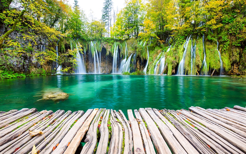 Waterfalls cascading into turquoise lake at Plitvice National Park, Croatia.