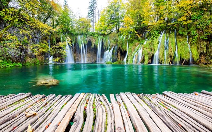 Waterfalls cascading into turquoise lake at Plitvice National Park, Croatia.