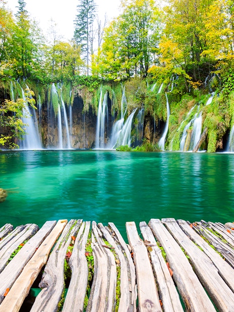 Waterfalls cascading into turquoise lake at Plitvice National Park, Croatia.