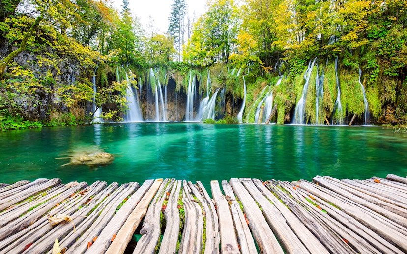 Waterfalls cascading into turquoise lake at Plitvice National Park, Croatia.