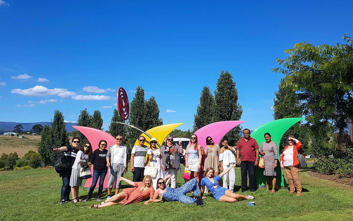Group enjoying Yarra Valley tour with colorful sculptures and scenic landscape.