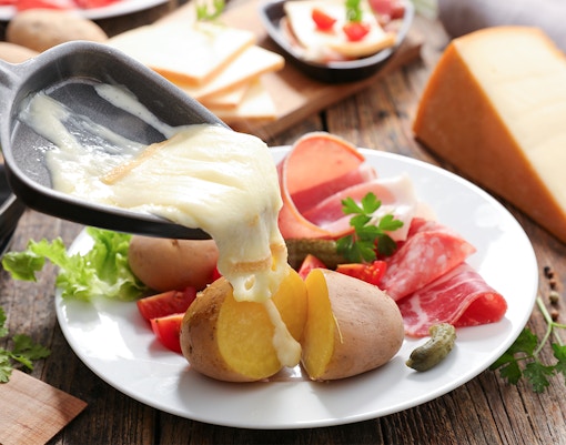 Raclette dining experience at Restaurant Rigi Chänzeli, overlooking Swiss Alps.