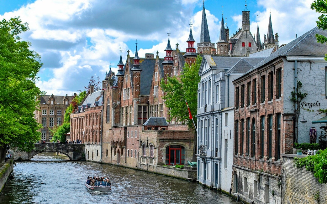 Boat ride on the Groenerei canal in Bruges with historic buildings and bridge.