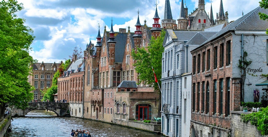 Boat ride on the Groenerei canal in Bruges with historic buildings and bridge.