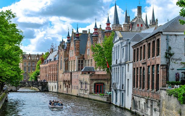 Boat ride on the Groenerei canal in Bruges with historic buildings and bridge.