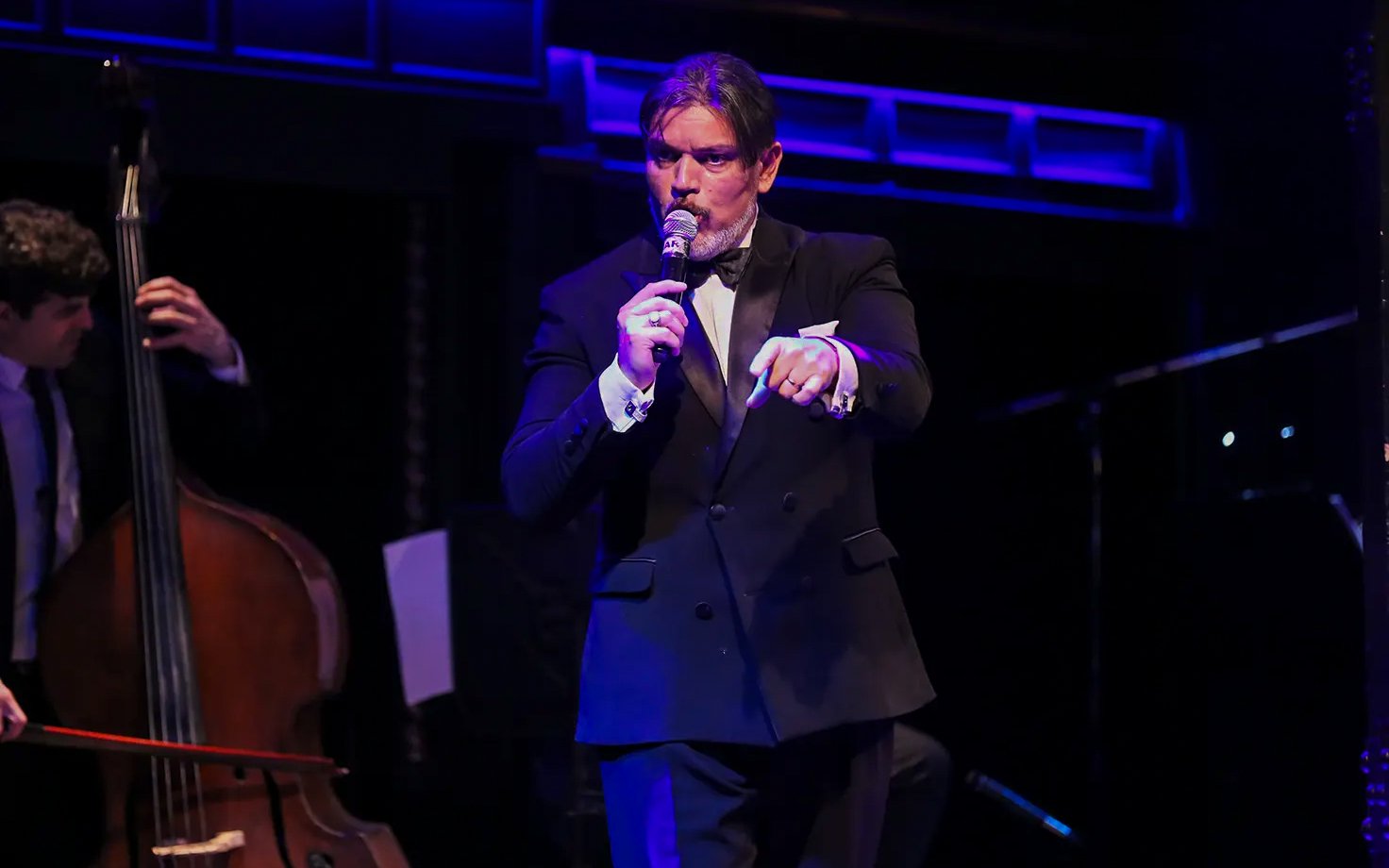 Musician singing at El Querandí Tango Show with double bass player in Buenos Aires.