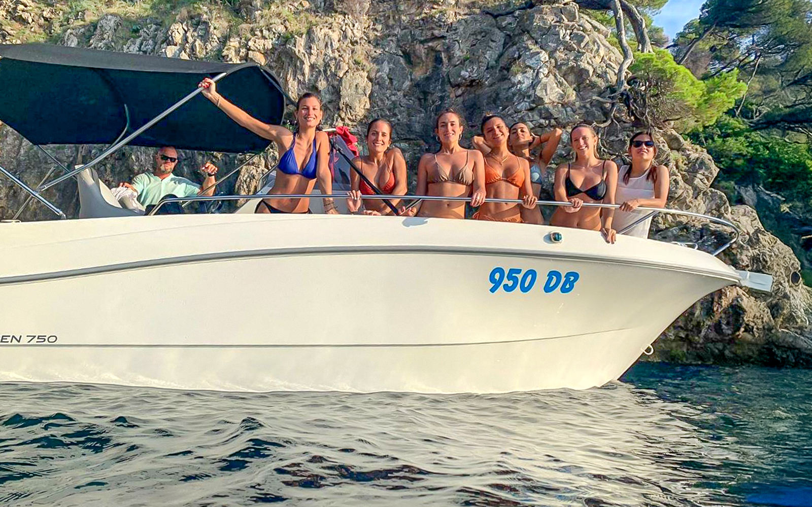 Guests on a boat tour near rocky cliffs, enjoying the view of blue caves.