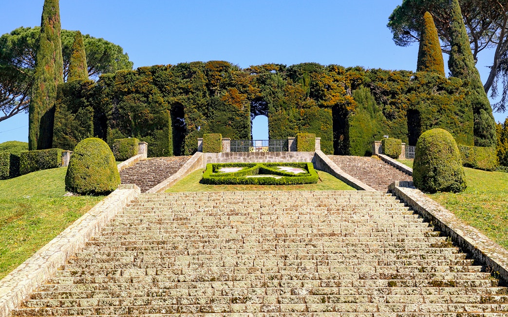 Stone steps leading to Castel Gandolfo's Secret Garden entrance, surrounded by manicured hedges.