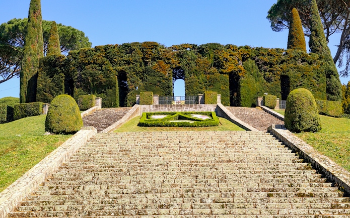 Stone steps leading to Castel Gandolfo's Secret Garden entrance, surrounded by manicured hedges.