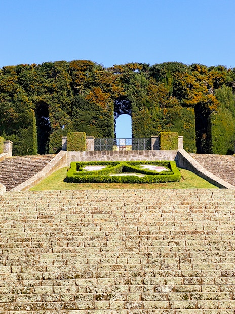 Stone steps leading to Castel Gandolfo's Secret Garden entrance, surrounded by manicured hedges.