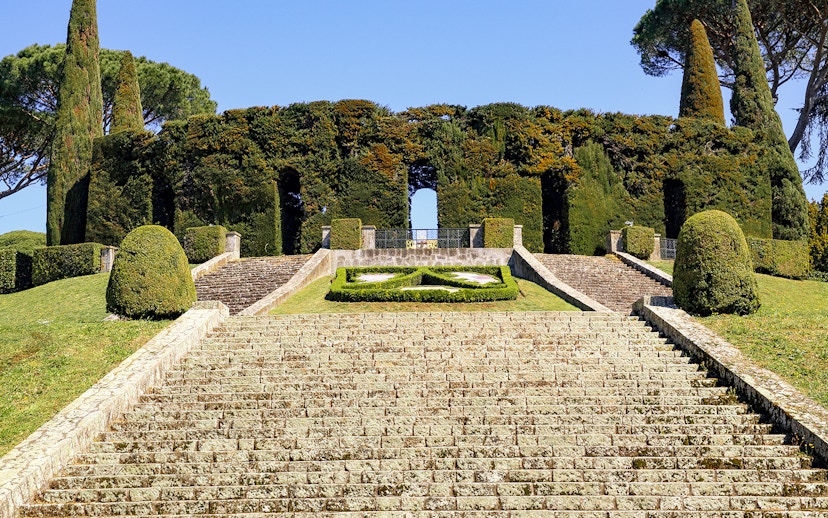 Stone steps leading to Castel Gandolfo's Secret Garden entrance, surrounded by manicured hedges.