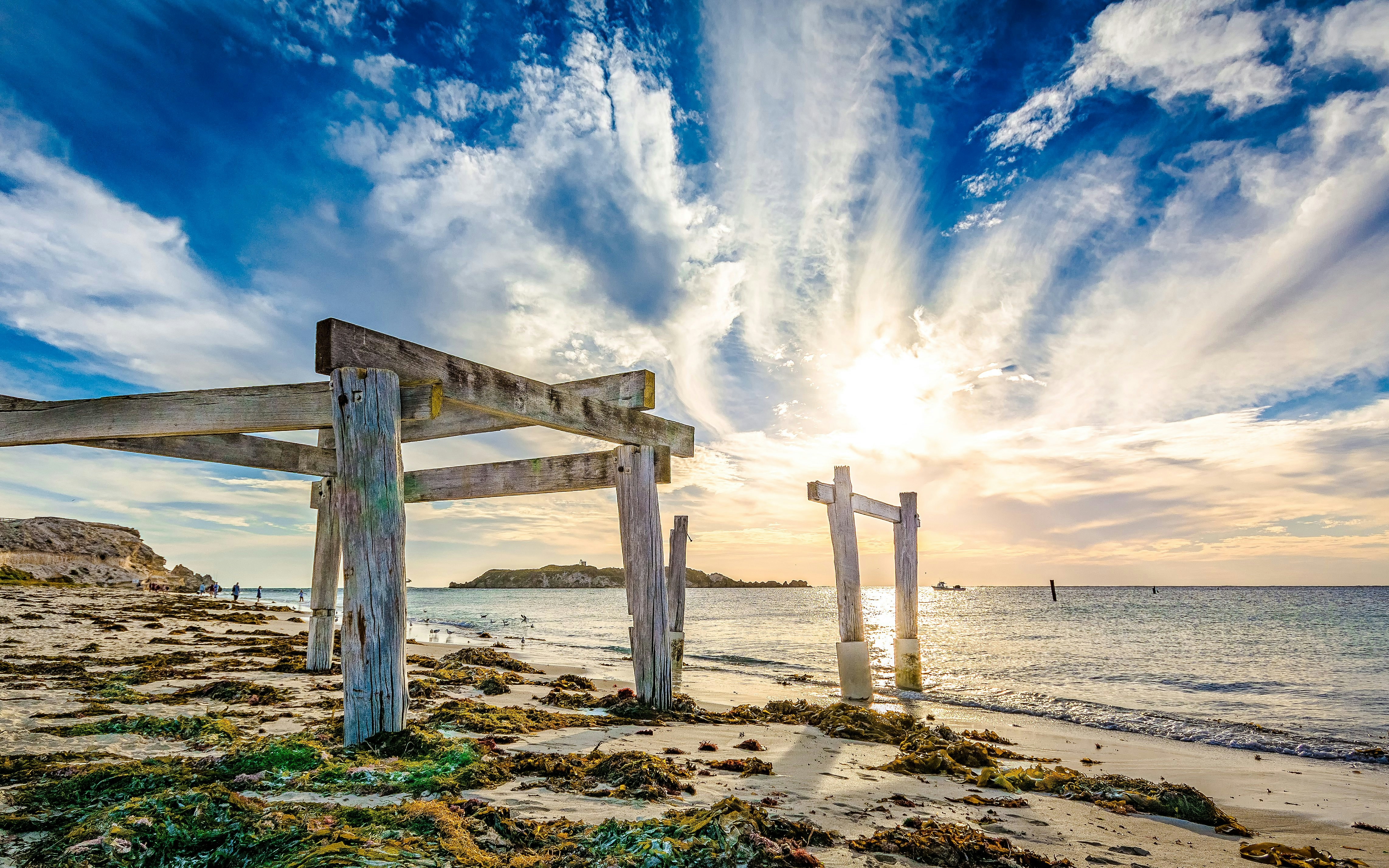 Old wooden jetty remains on the beach at Hamelin Bay with ocean and sky in the background.