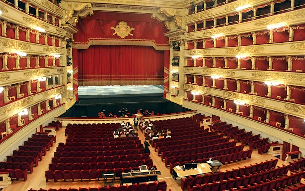 Interior of La Scala Theatre in Milan with red velvet seats and ornate balconies.