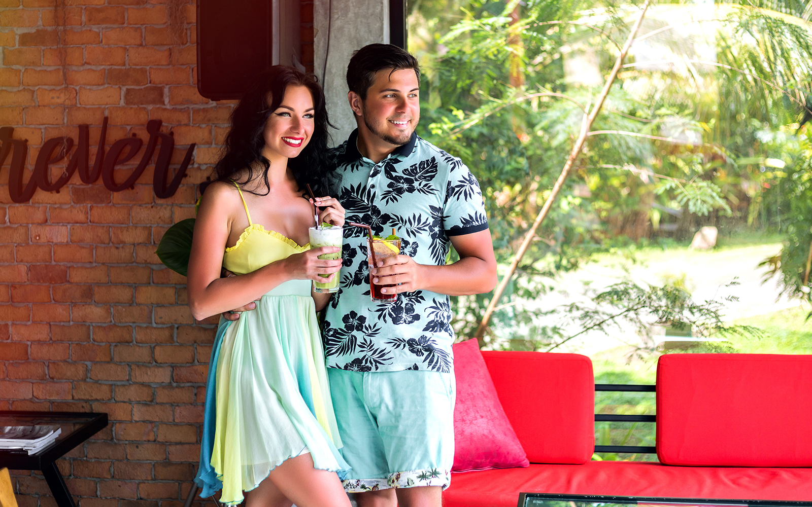 Man wearing a floral t-shirt and woman wearing a fitted dress inside home