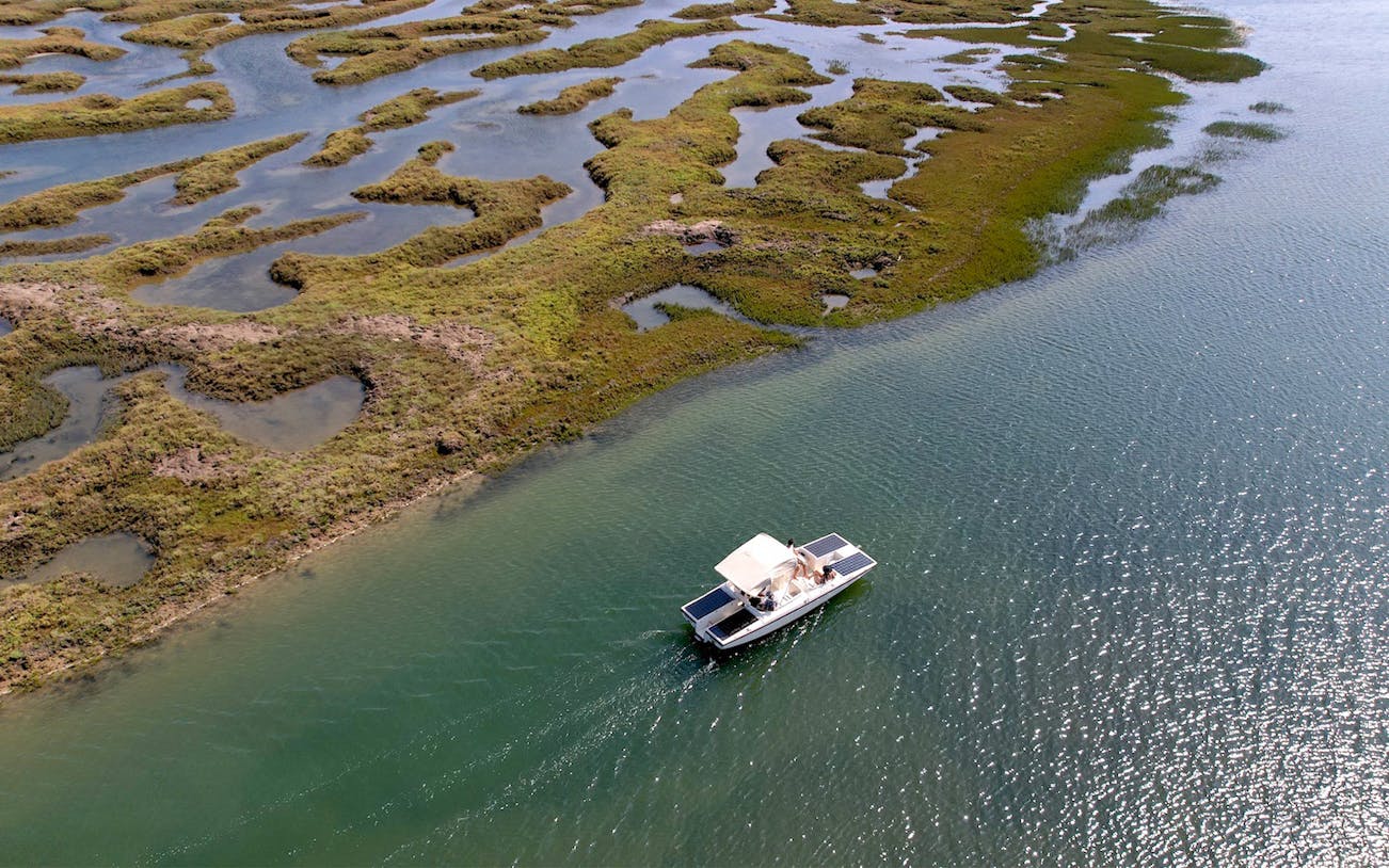 Eco-friendly boat navigating Ria Formosa's winding waterways in Algarve, Portugal.