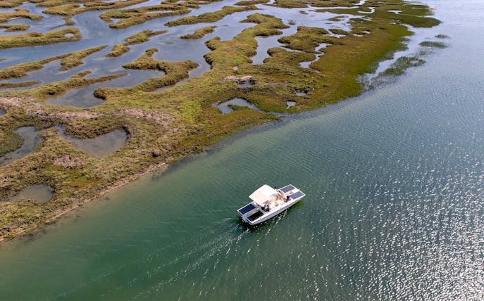Eco-friendly boat navigating Ria Formosa's winding waterways in Algarve, Portugal.