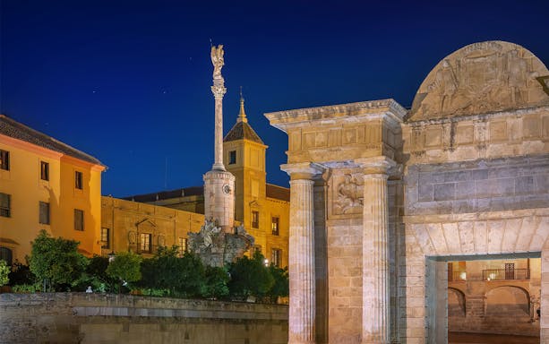 Night view of Roman Bridge Gate and San Rafael Column in Córdoba, Spain.