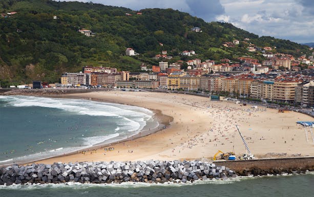 San Sebastian beach with people and cityscape in the background.