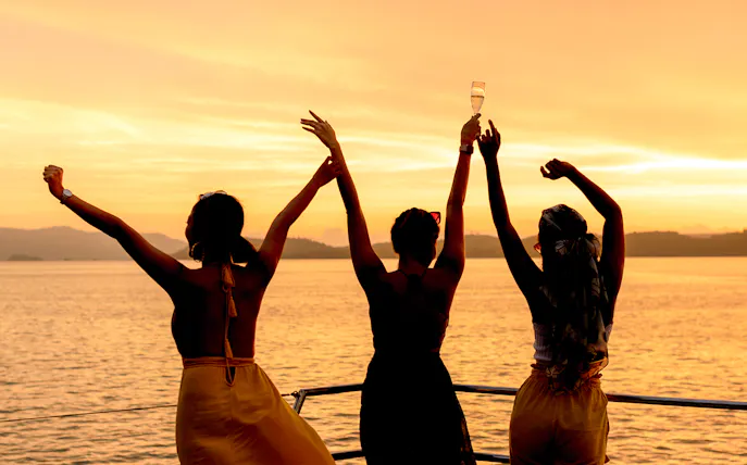 Three people enjoying sunset drinks on a boat in Athens.