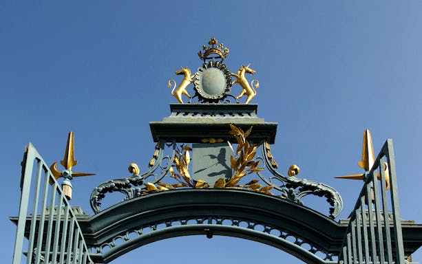 Ornate gate detail at Château de Maisons, featuring golden unicorns and decorative elements.
