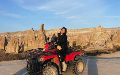 Person riding an ATV in Cappadocia with rock formations in the background.