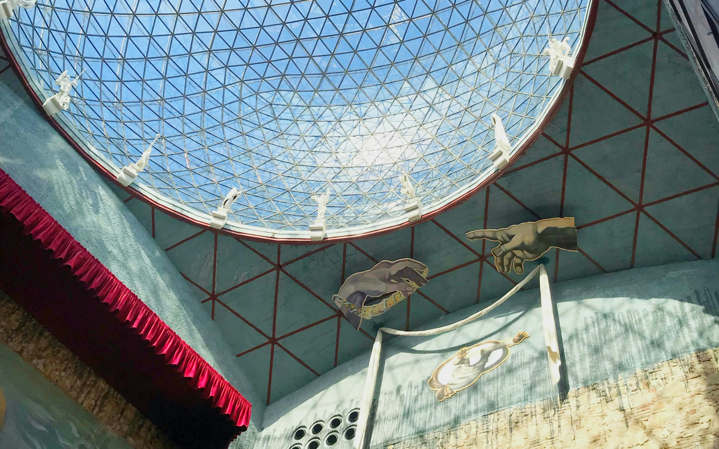 Interior view of glass dome in Dalí Museum, Spain, with artistic hand sculptures.