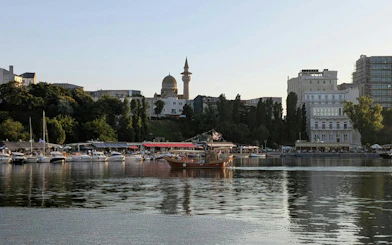 Harbor view with boats and mosque in Constanta, Romania, part of self-guided city exploration game.