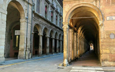 Arched portico in Piazza Rossini, Bologna, part of the self-guided city exploration game.